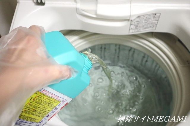 洗濯槽に塩素系クリーナーを注いでいる様子