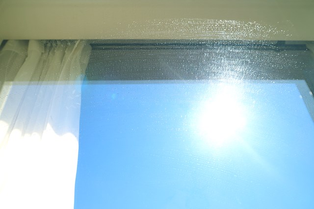 窓に映った青い空と拭きムラ